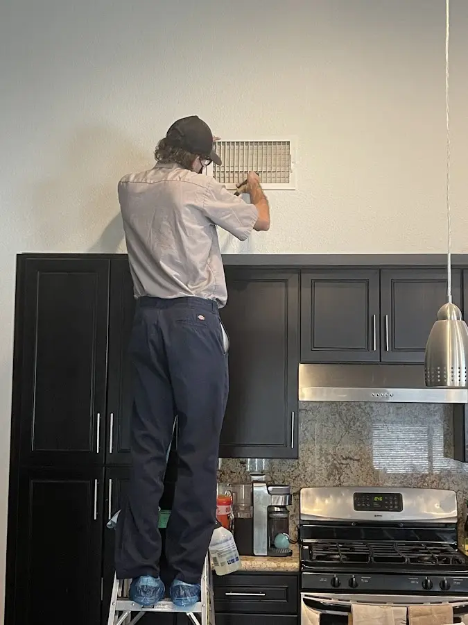 Technician inspecting an air vent during HVAC service in Cloverdale